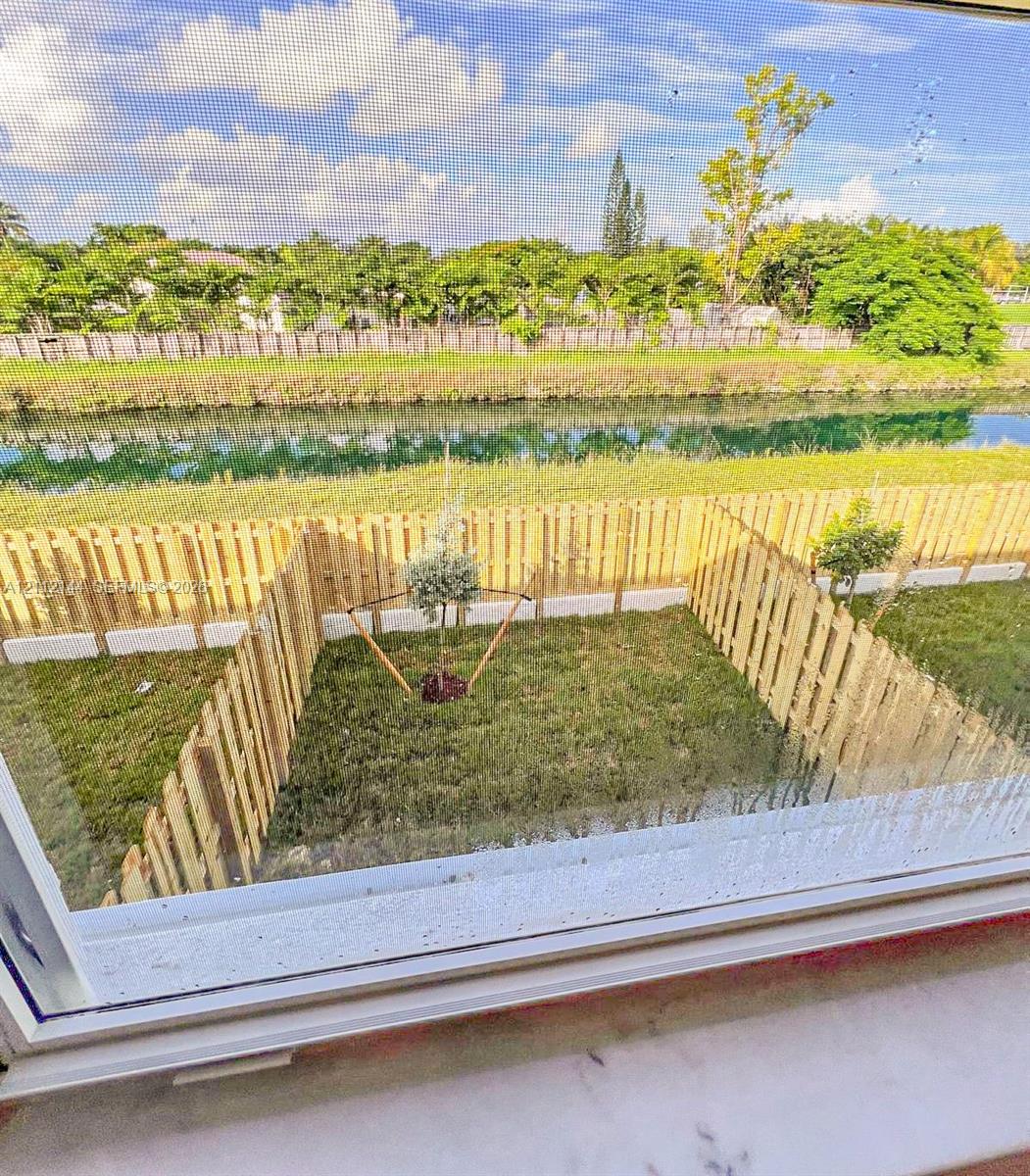 Fenced backyard featuring a manicured lawn, established landscaping, and direct water frontage
