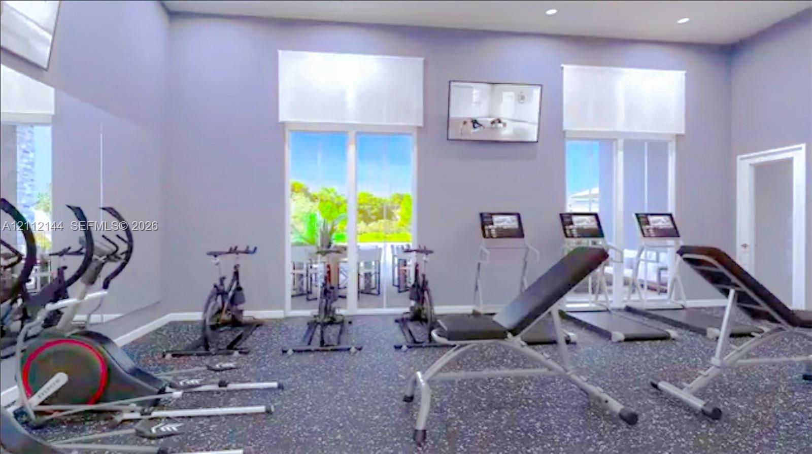 Fitness room featuring resilient rubber flooring, wall-to-wall mirrors, and dual glass paneled doors providing natural light