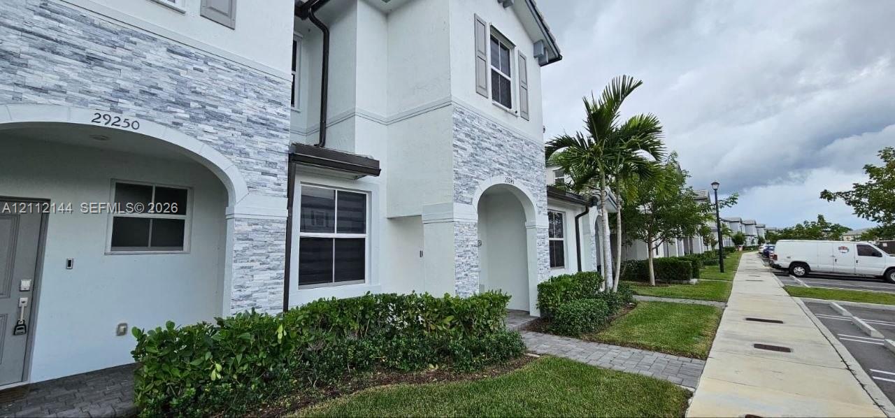 Exterior facade featuring white stucco finish, stacked stone veneer accents, arched entryways, and shuttered windows