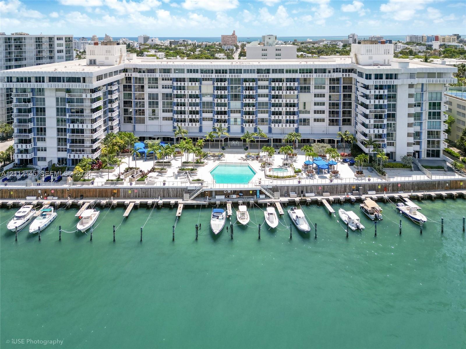 Waterfront multi-story residential building featuring a private deep-water dock, integrated swimming pool, spa, and exterior balcony access for residential units Waterfront multi-story residential building featuring a private deep-water dock, integrated swimming pool, spa, and exterior balcony access for residential units