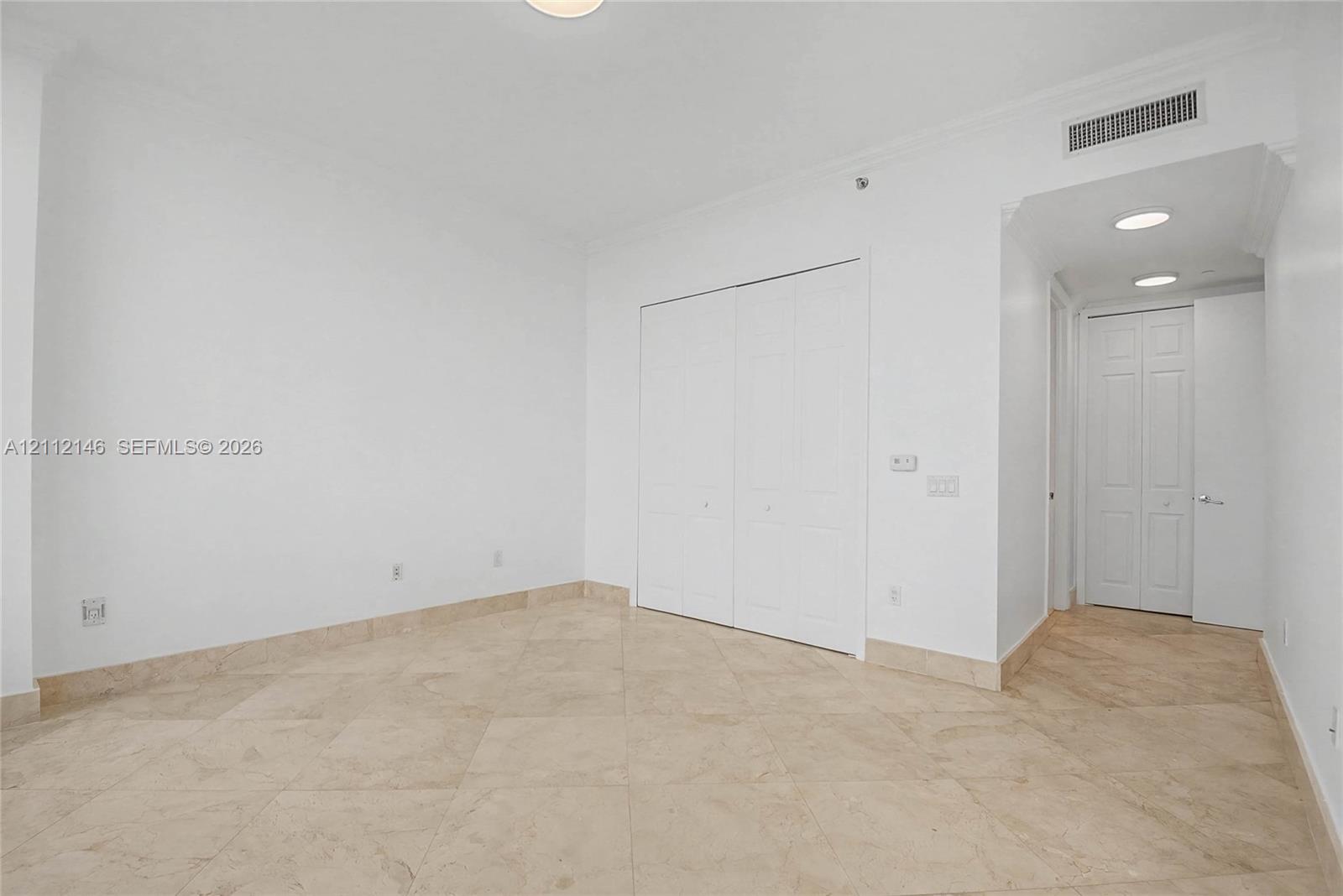 Neutral interior space featuring polished tile flooring, recessed lighting, and dual-panel closet doors