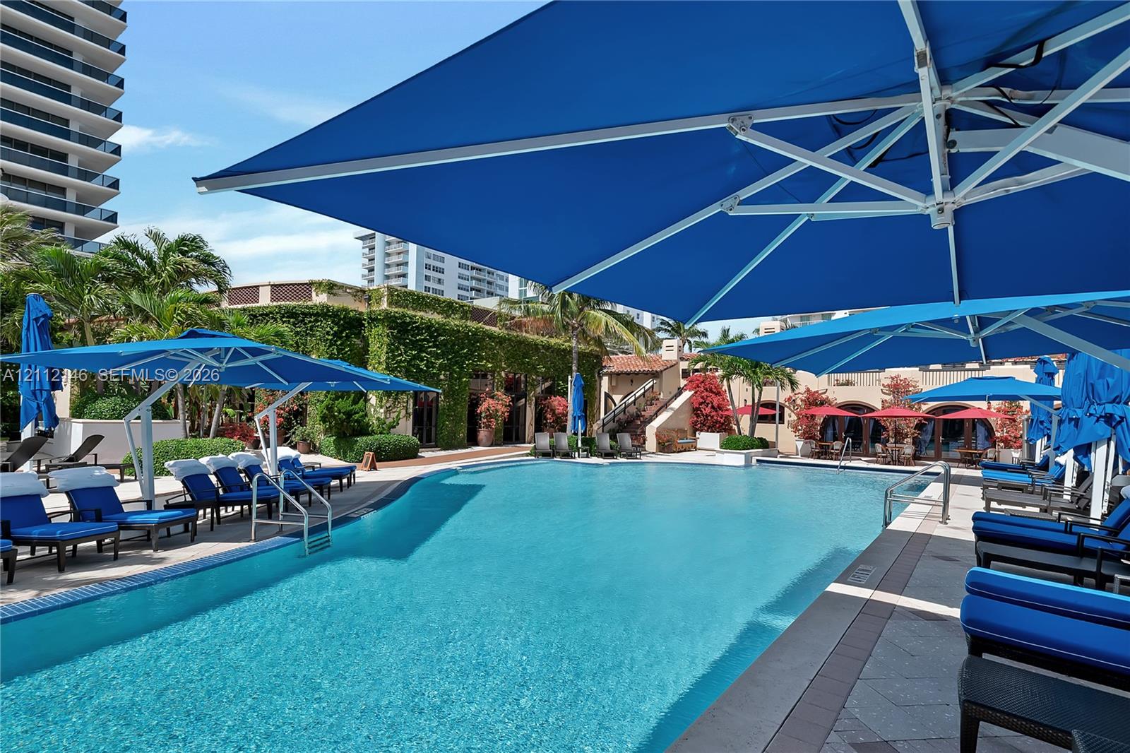 Swimming pool featuring tile edging, stone-paver decking, and structural shade canopies