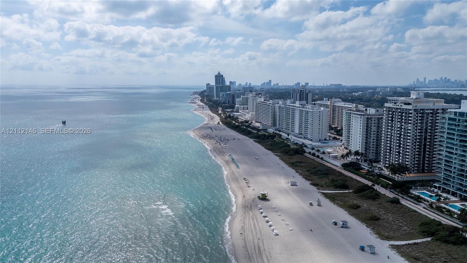 Aerial coastal perspective featuring a direct sandy shoreline and clear ocean waters