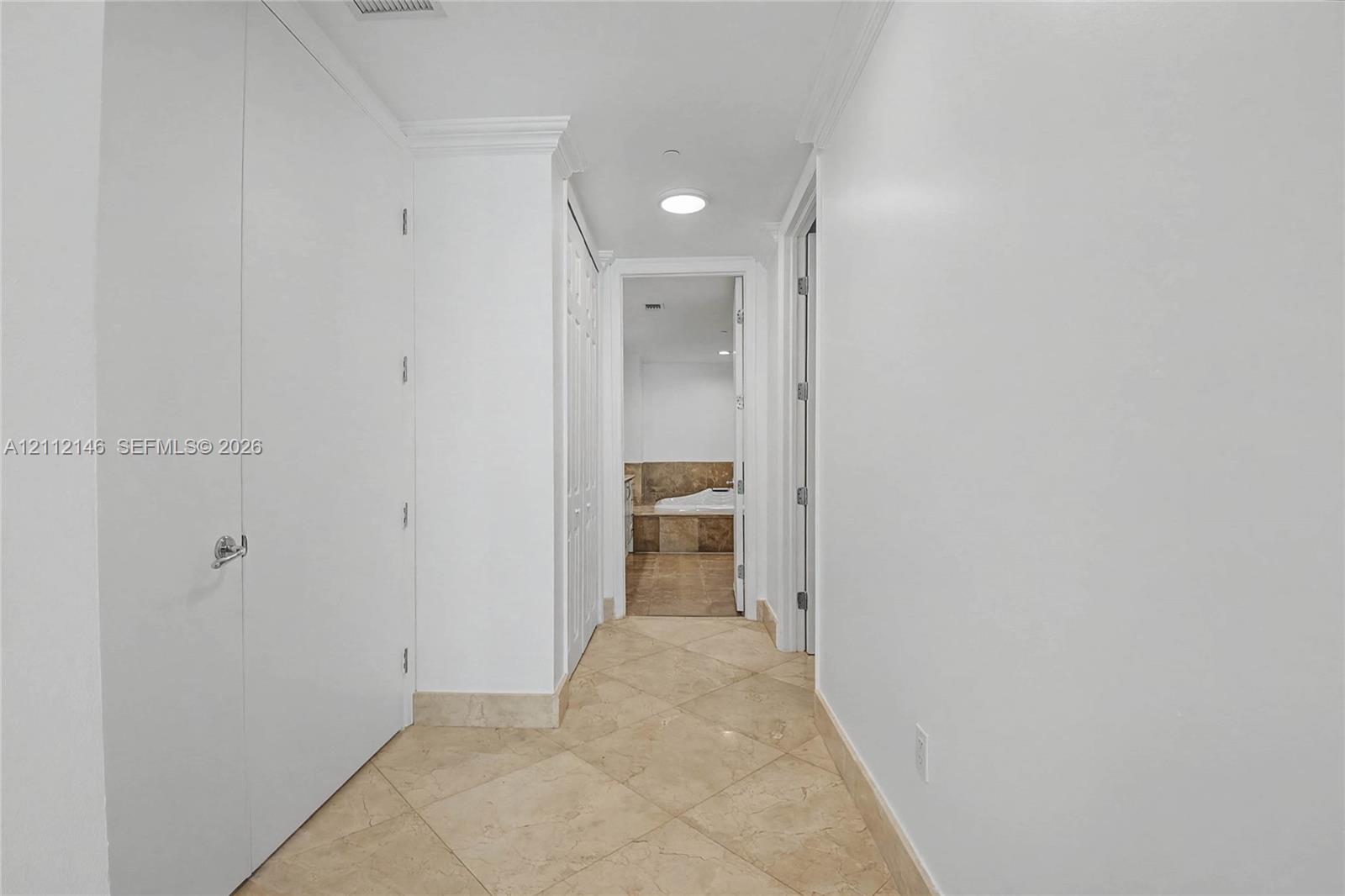 Hallway featuring neutral tile flooring laid on a diagonal, crisp white walls, crown molding, and recessed lighting