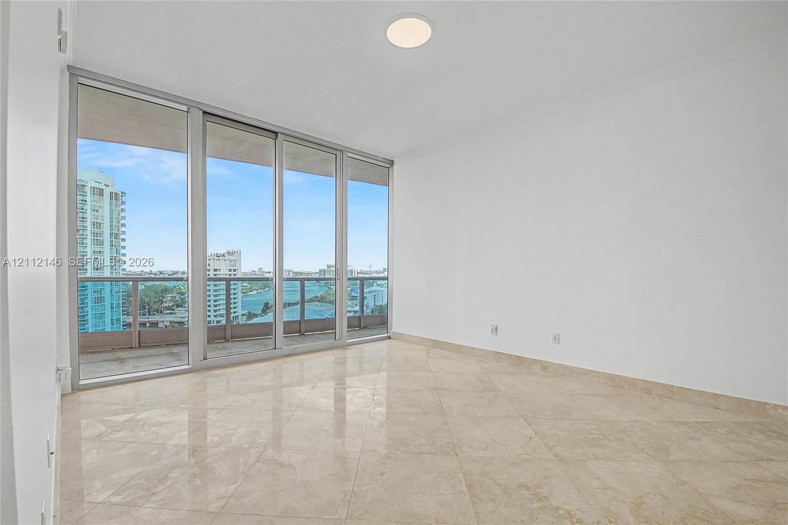 Floor-to-ceiling sliding glass doors, polished stone tile flooring, and a private balcony with metal railing