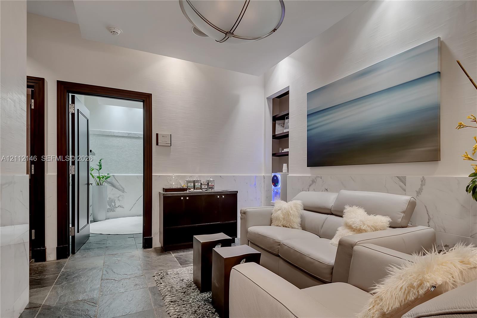 Stone tile flooring, wainscoting with integrated stone-finish panels, recessed shelving, and a spherical semi-flush mount light fixture