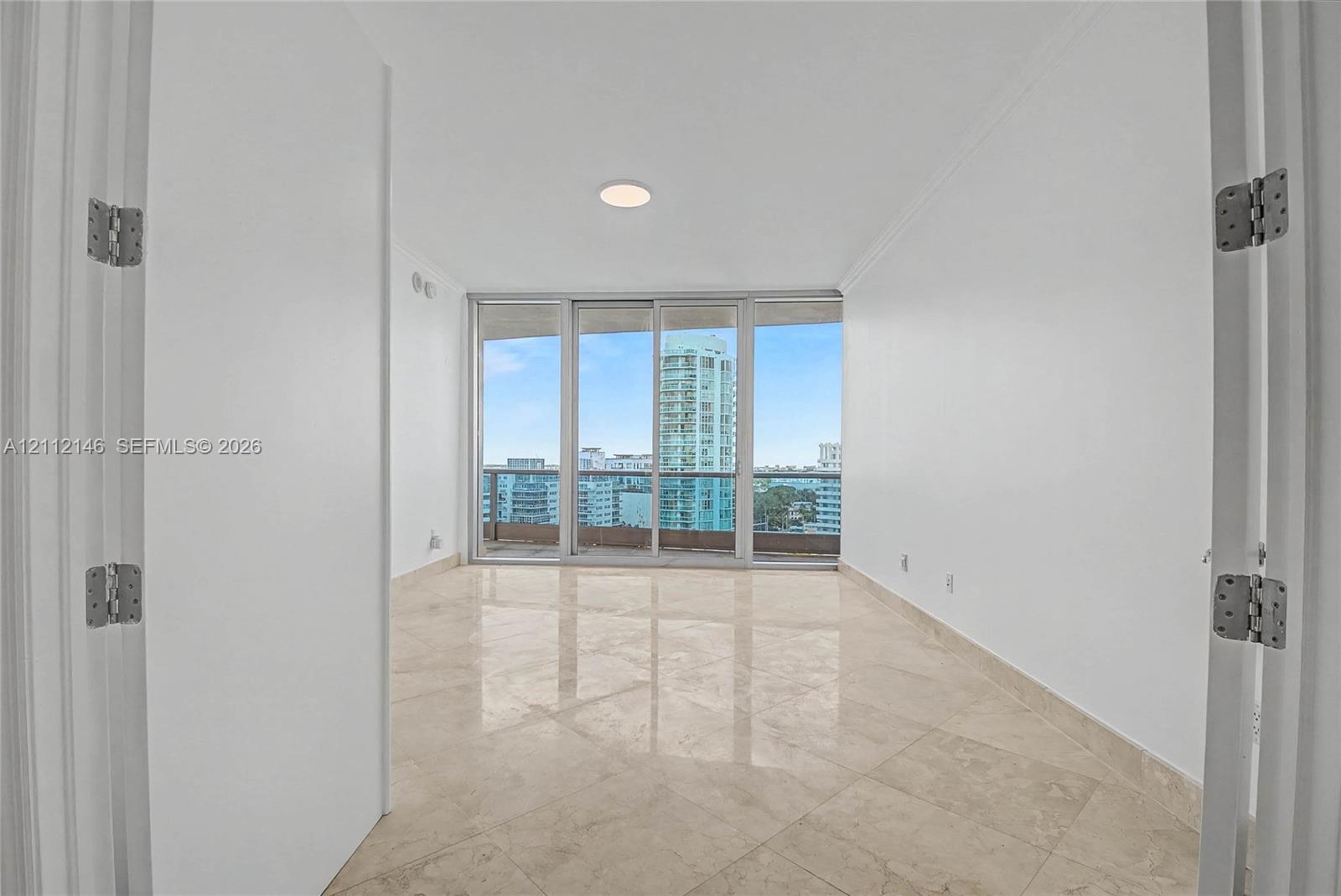 Polished stone flooring, expansive floor-to-ceiling glass sliding doors, and private balcony access