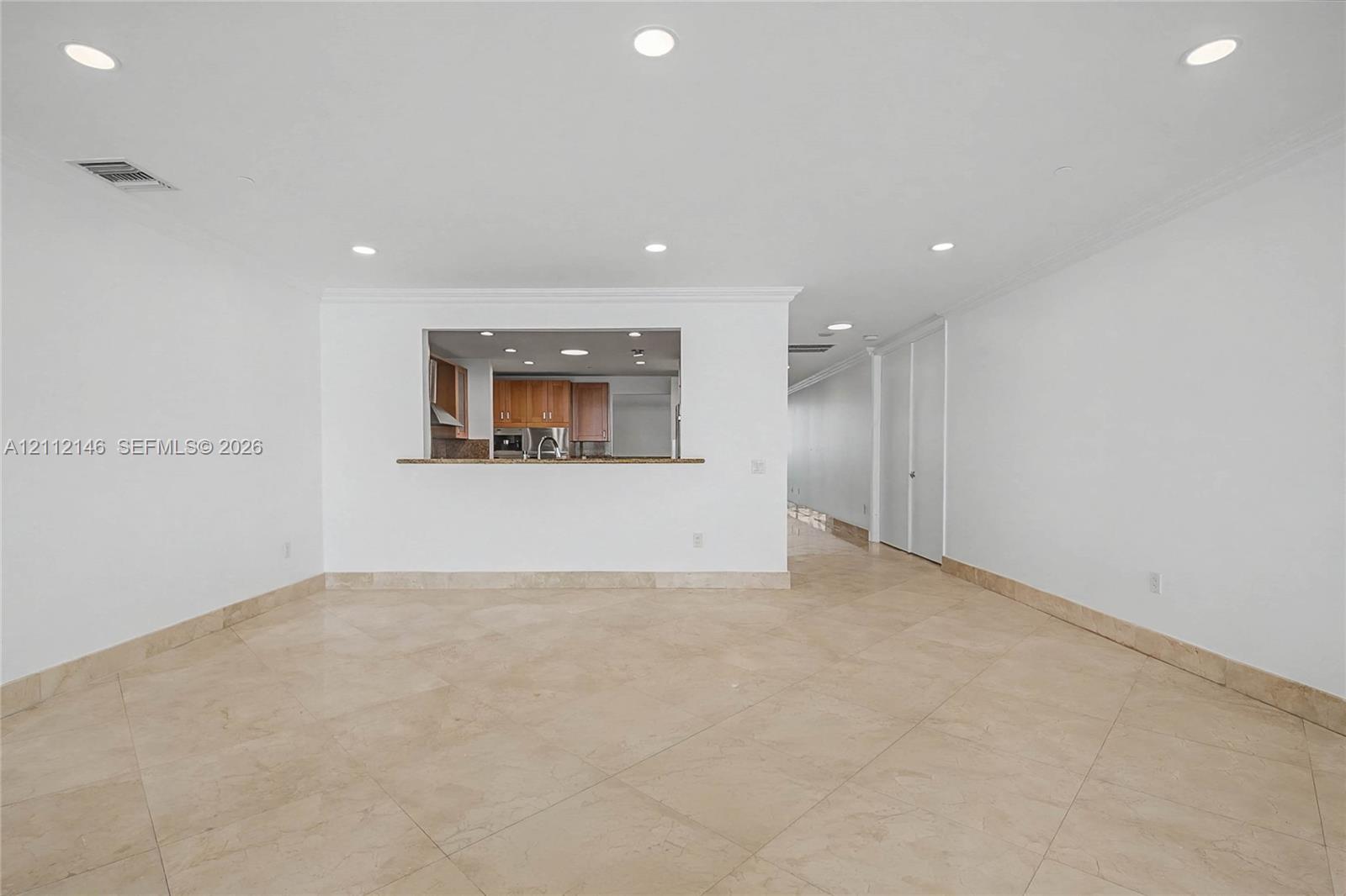 Open floor plan featuring tile flooring, recessed lighting, and a kitchen pass-through with a breakfast bar
