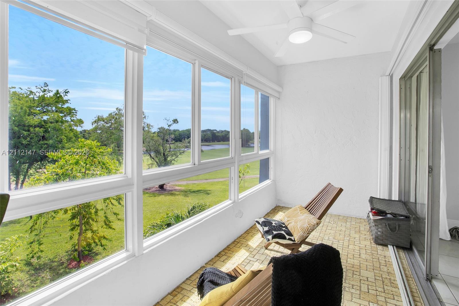 Enclosed sunroom featuring expansive windows, brick-patterned flooring, a ceiling-mounted light fixture, and textured wall finishes