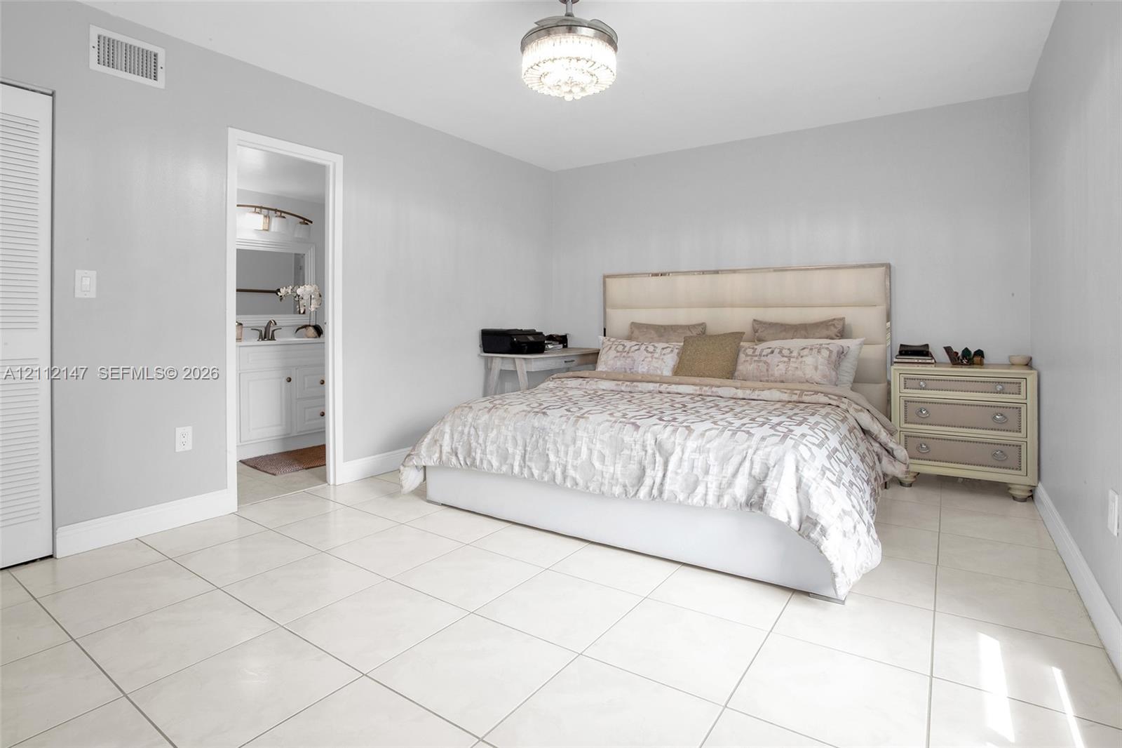 Neutral-toned interior featuring large-format tile flooring, a crystal-accented flush mount ceiling light, and a double-door closet