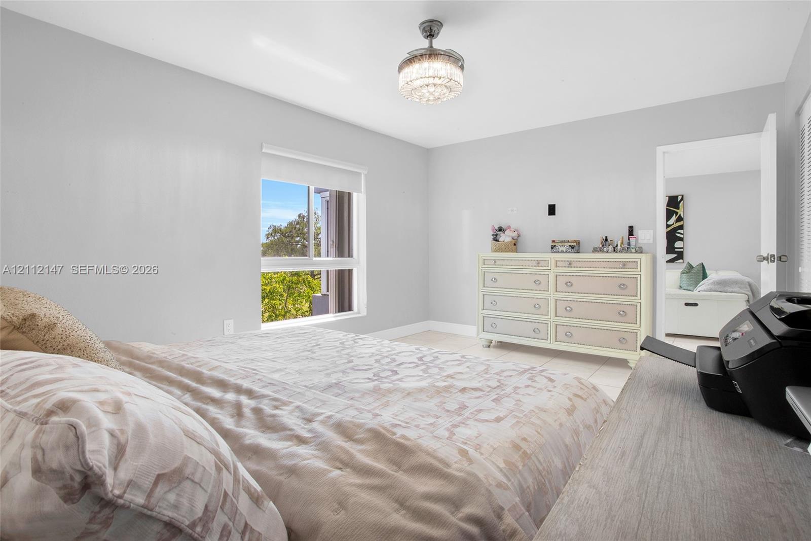 Neutral-toned interior featuring expansive natural light, a ceiling-mounted crystal-accented chandelier, and a single-hung window