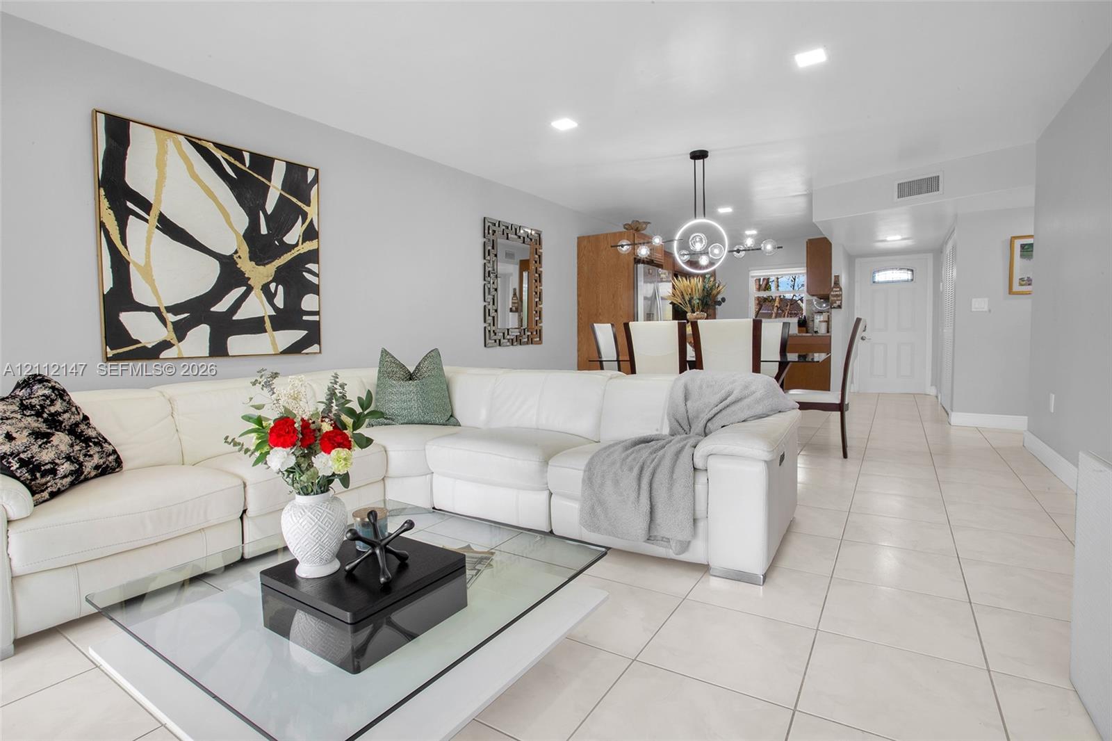 Large format neutral tile flooring, recessed ceiling lighting, and contemporary circular chandelier Large format neutral tile flooring, recessed ceiling lighting, and contemporary circular chandelier