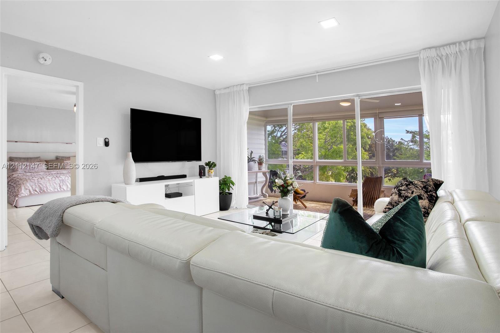 Living area featuring large-format tile flooring, recessed lighting, and expansive floor-to-ceiling sliding glass doors opening to a covered patio