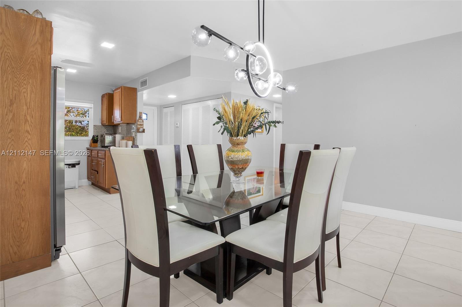 Dining area featuring large-format ceramic tile flooring, a modern multi-globe chandelier, and recessed lighting