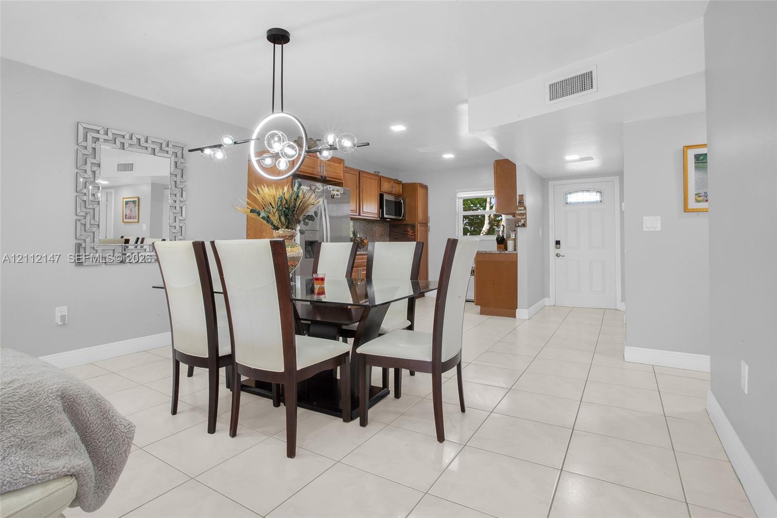 Open concept floor plan with tile flooring, recessed lighting, modern circular chandelier, and kitchen cabinetry