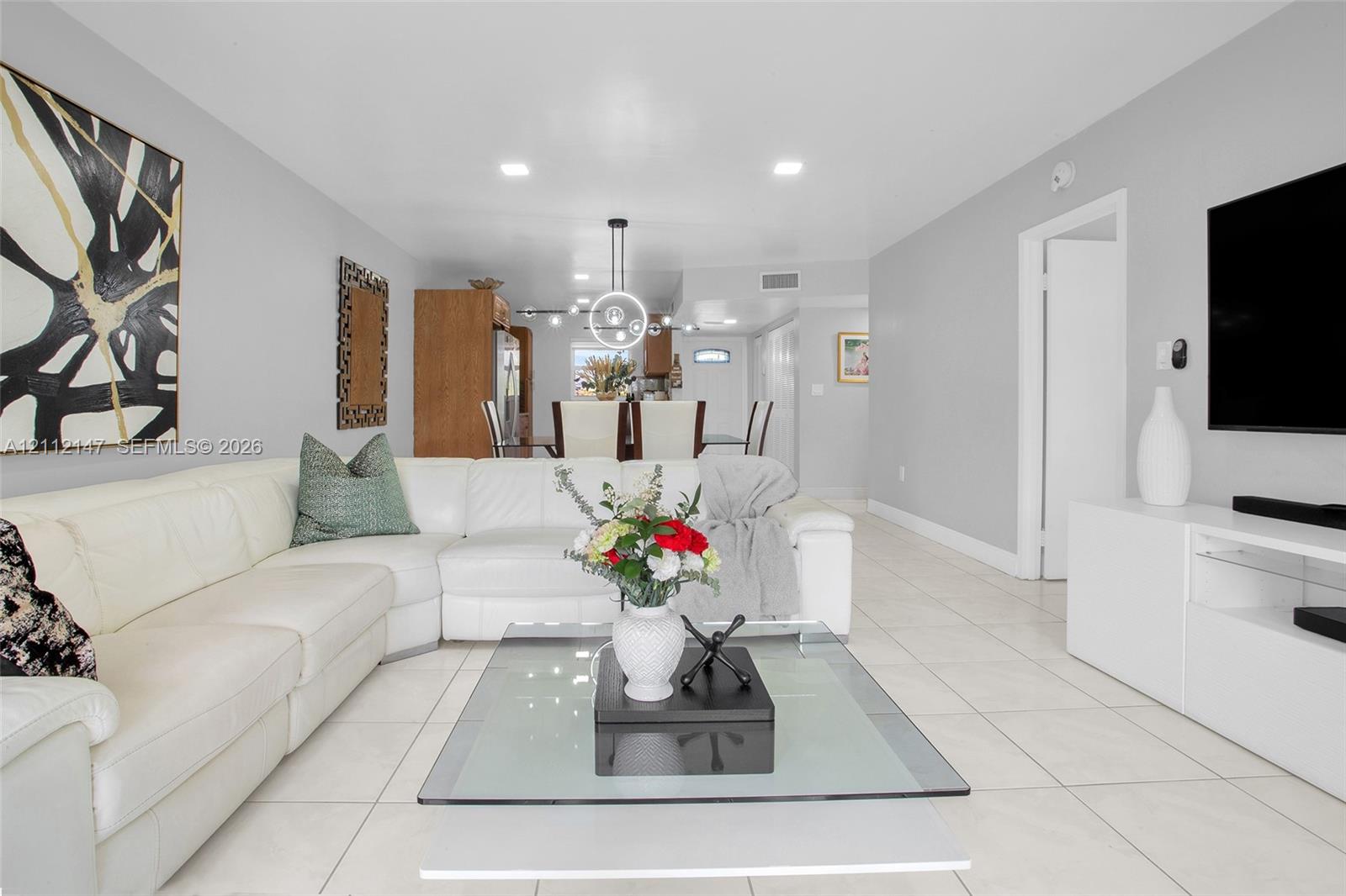 Large format tile flooring, recessed lighting, and contemporary ring chandelier
