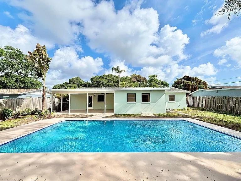 In-ground rectangular swimming pool featuring a concrete deck and a covered patio area with vertical support pillars In-ground rectangular swimming pool featuring a concrete deck and a covered patio area with vertical support pillars