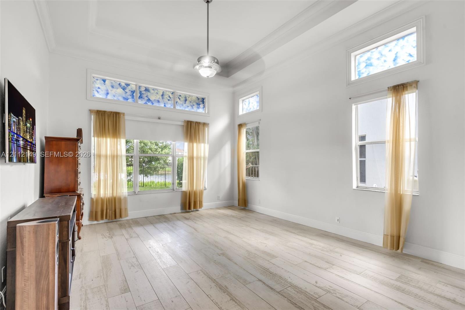High ceilings with crown molding, wood-finish flooring, transom windows, and a central ceiling fan