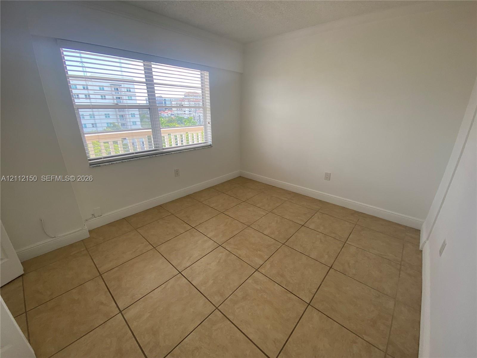 Neutral-toned ceramic tile flooring, expansive window with horizontal blinds, and neutral wall paint