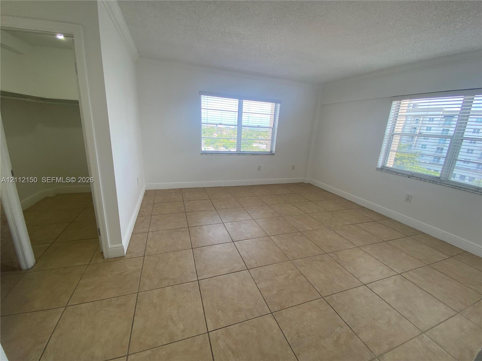 Storage space featuring large-format ceramic tile flooring, built-in shelving, and a ceiling-mounted light fixture