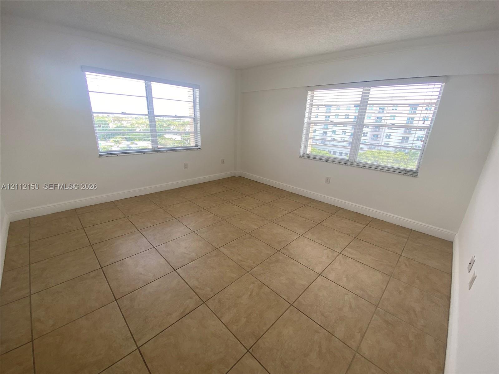 Interior space featuring large-format neutral tile flooring, expansive windows, and crisp white walls