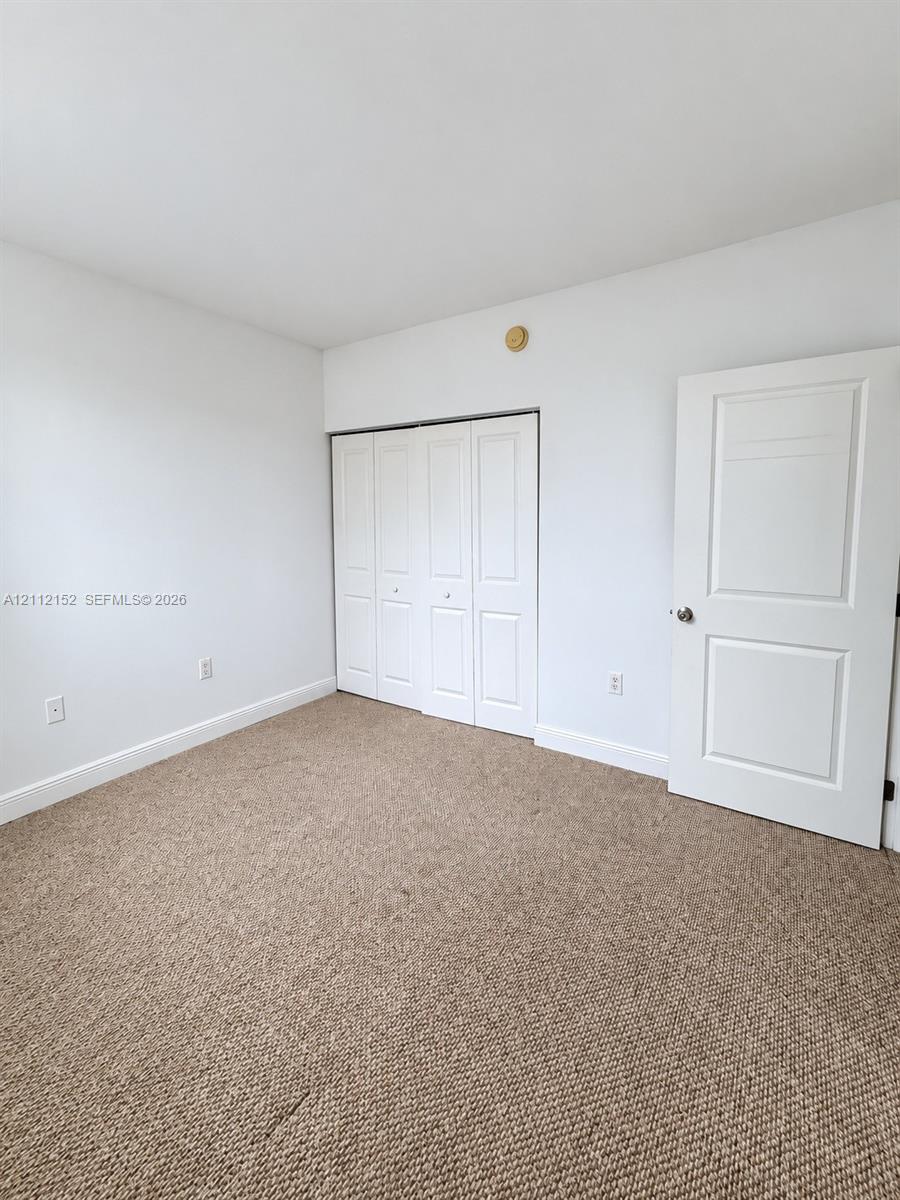 Neutral-toned carpeting, white walls, folding-panel closet doors, and a solid-core two-panel interior door