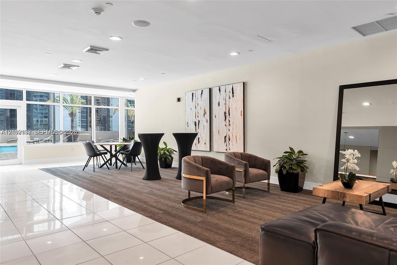 Expansive interior space featuring large-format polished tile flooring, wall-to-wall carpeting, recessed ceiling lighting, and floor-to-ceiling windows