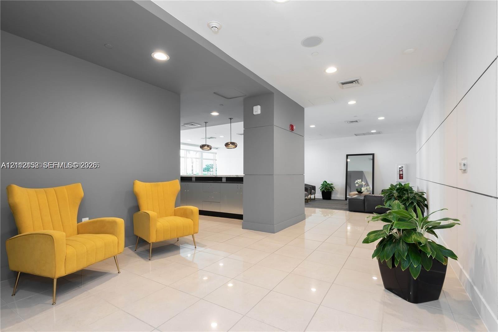 Open-concept interior featuring large-format tile flooring, recessed ceiling lighting, a matte grey architectural column, and panel-accented wall detailing