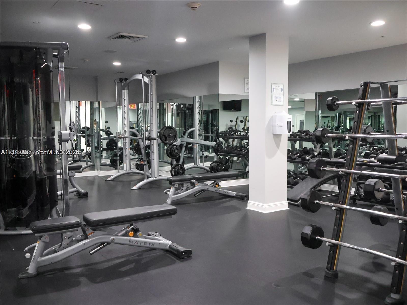 Fitness center featuring rubberized flooring, recessed ceiling lighting, and floor-to-ceiling mirrored walls