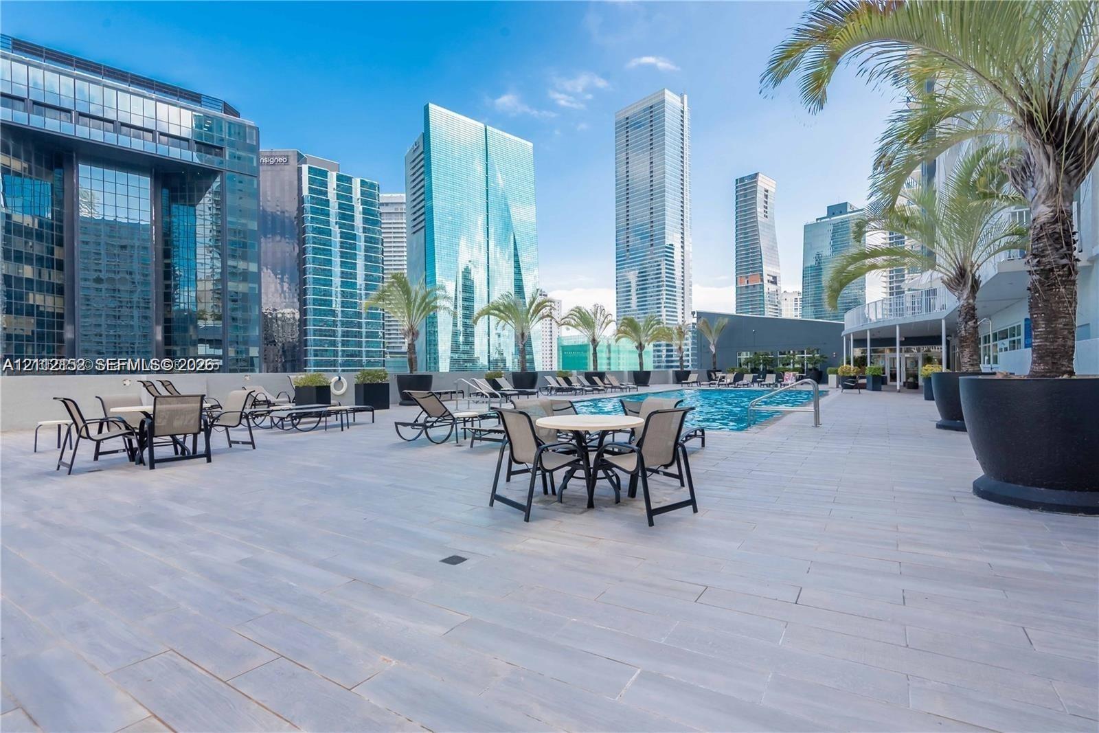 Rooftop terrace featuring tile flooring, a swimming pool, and large potted palms