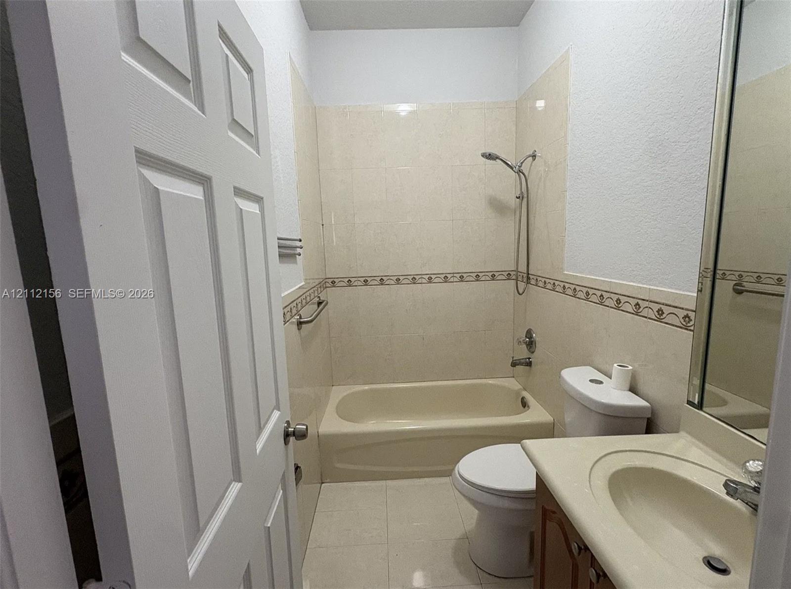 Bathroom featuring a soaking tub, tile surround with decorative inlay, integrated vanity with a molded basin, and chrome fixtures