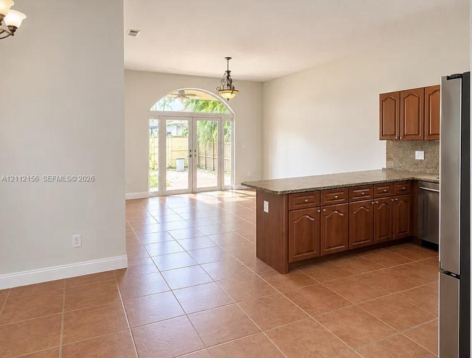 Kitchen featuring wood cabinetry, stone-finish countertops, tile flooring, and arched glass doors