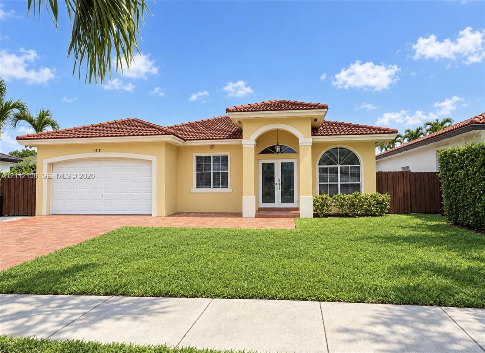 Stucco exterior with a tiled roof, arched entryway, brick-paver driveway, and a multi-paned arched window Stucco exterior with a tiled roof, arched entryway, brick-paver driveway, and a multi-paned arched window