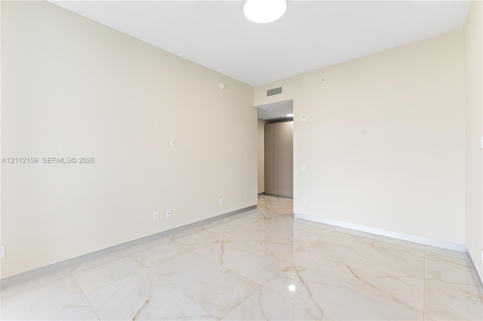 Neutral interior featuring large-format tile flooring with marble-pattern veining, flush-mount circular lighting, and smooth-finish walls