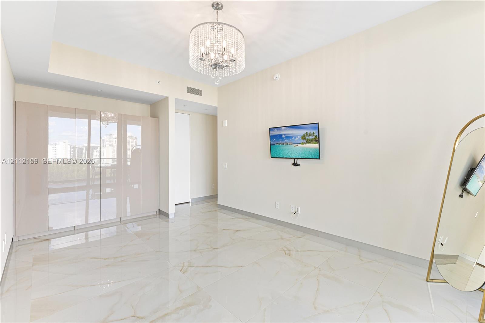 Polished stone flooring, floor-to-ceiling glass wall panels, and an ornate crystal chandelier