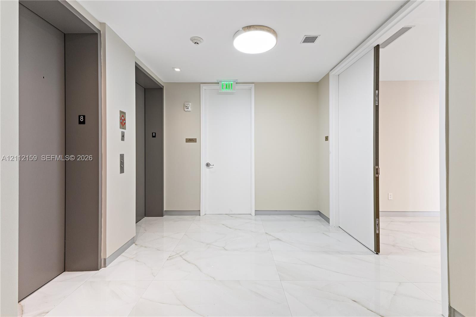 Common area featuring large-format white stone-finish tile flooring, dual elevators with metallic finishes, and recessed ceiling lighting Common area featuring large-format white stone-finish tile flooring, dual elevators with metallic finishes, and recessed ceiling lighting