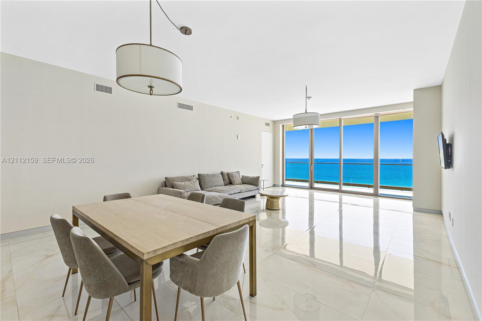 Floor-to-ceiling glass panel windows, polished tile flooring, pendant lighting fixtures, and an exterior balcony Floor-to-ceiling glass panel windows, polished tile flooring, pendant lighting fixtures, and an exterior balcony