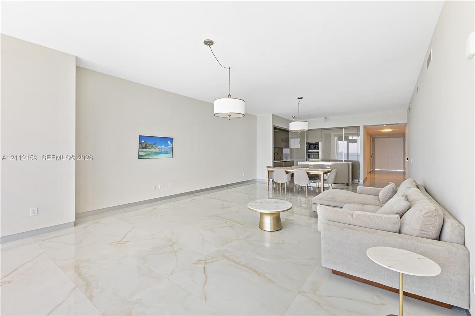 Large-format neutral flooring with veining, dual modern drum pendant lighting, and built-in kitchen cabinetry