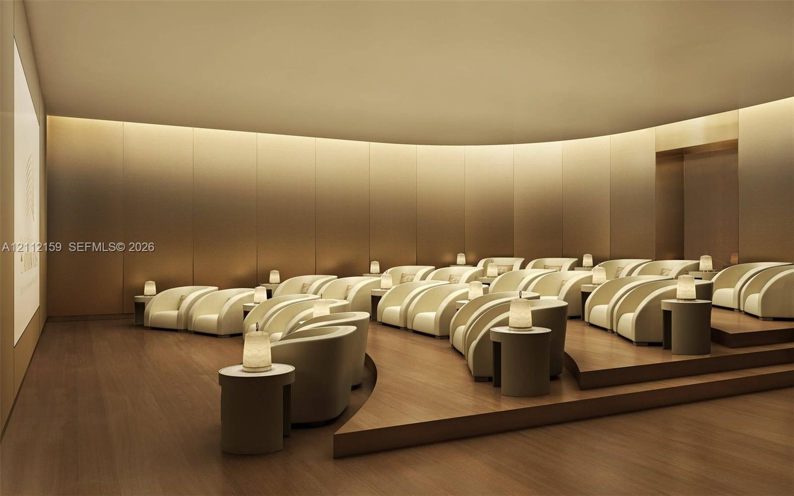 Curved room featuring wood-finish flooring, tiered platform seating, integrated cove lighting, and floor-to-ceiling metallic wall paneling