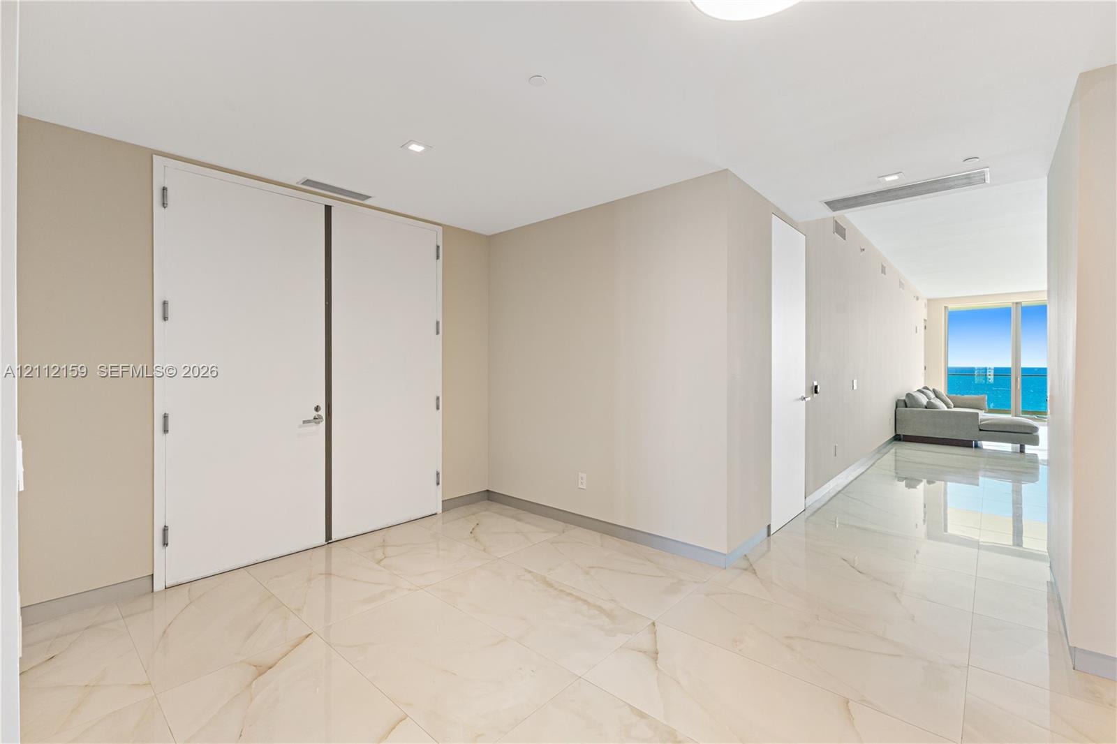 Large-format polished tile flooring with natural stone-style veining, high ceilings with recessed lighting, and expansive floor-to-ceiling windows featuring water scenery Large-format polished tile flooring with natural stone-style veining, high ceilings with recessed lighting, and expansive floor-to-ceiling windows featuring water scenery