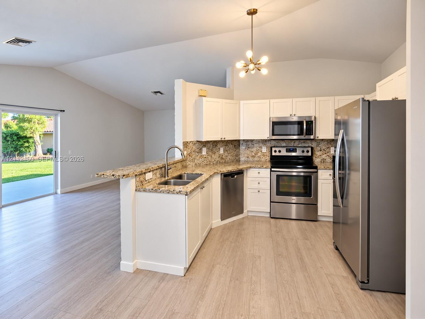 Kitchen featuring white cabinetry, stone-finish countertops, stainless steel appliances, wood-finish flooring, and vaulted ceilings
