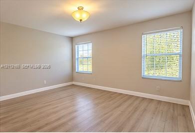 Neutral-toned walls, wood-finish flooring, two multi-pane windows with blinds, and an installed semi-flush mount light fixture Neutral-toned walls, wood-finish flooring, two multi-pane windows with blinds, and an installed semi-flush mount light fixture