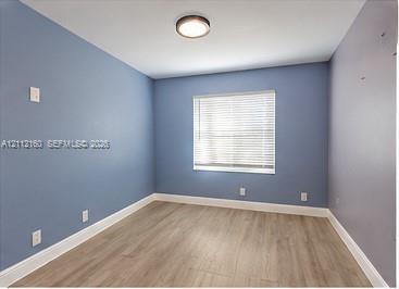 Room featuring wood-finish flooring, a single-window configuration with horizontal blinds, and a central flush-mount ceiling light fixture