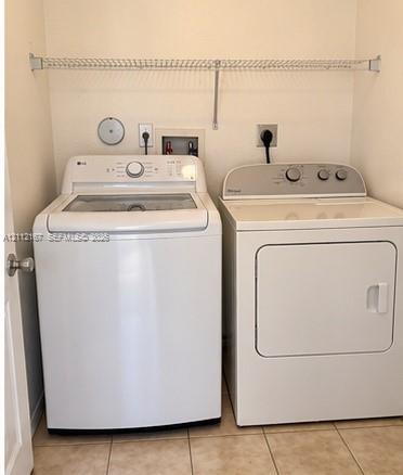 Laundry area featuring tile flooring, built-in wire shelving, and dedicated utility hookups