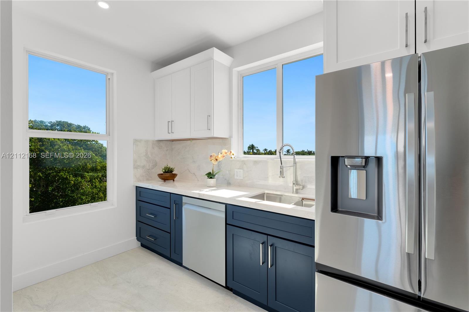 Kitchen featuring two-tone cabinetry, stone-finish countertops, stainless steel appliances, and large windows