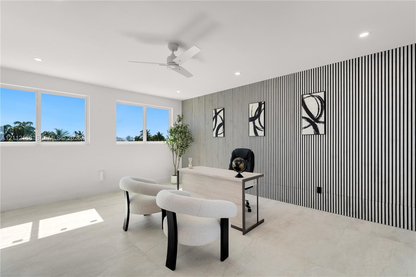 Room featuring large windows, neutral stone-finish flooring, recessed lighting, a modern ceiling fan, and a decorative vertical-slat accent wall