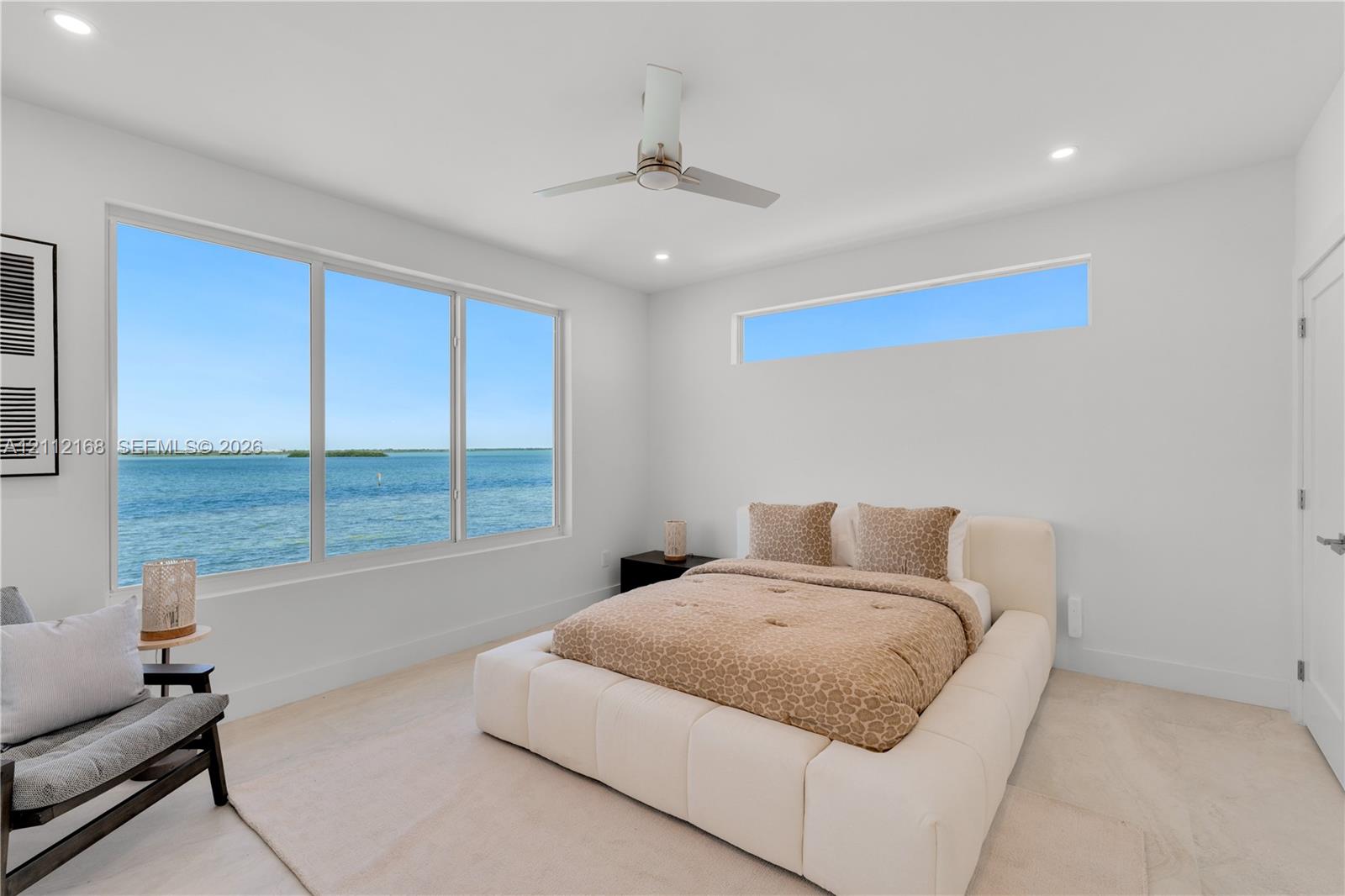 Large windows featuring water scenery, additional clerestory window, recessed lighting, and a modern ceiling fan