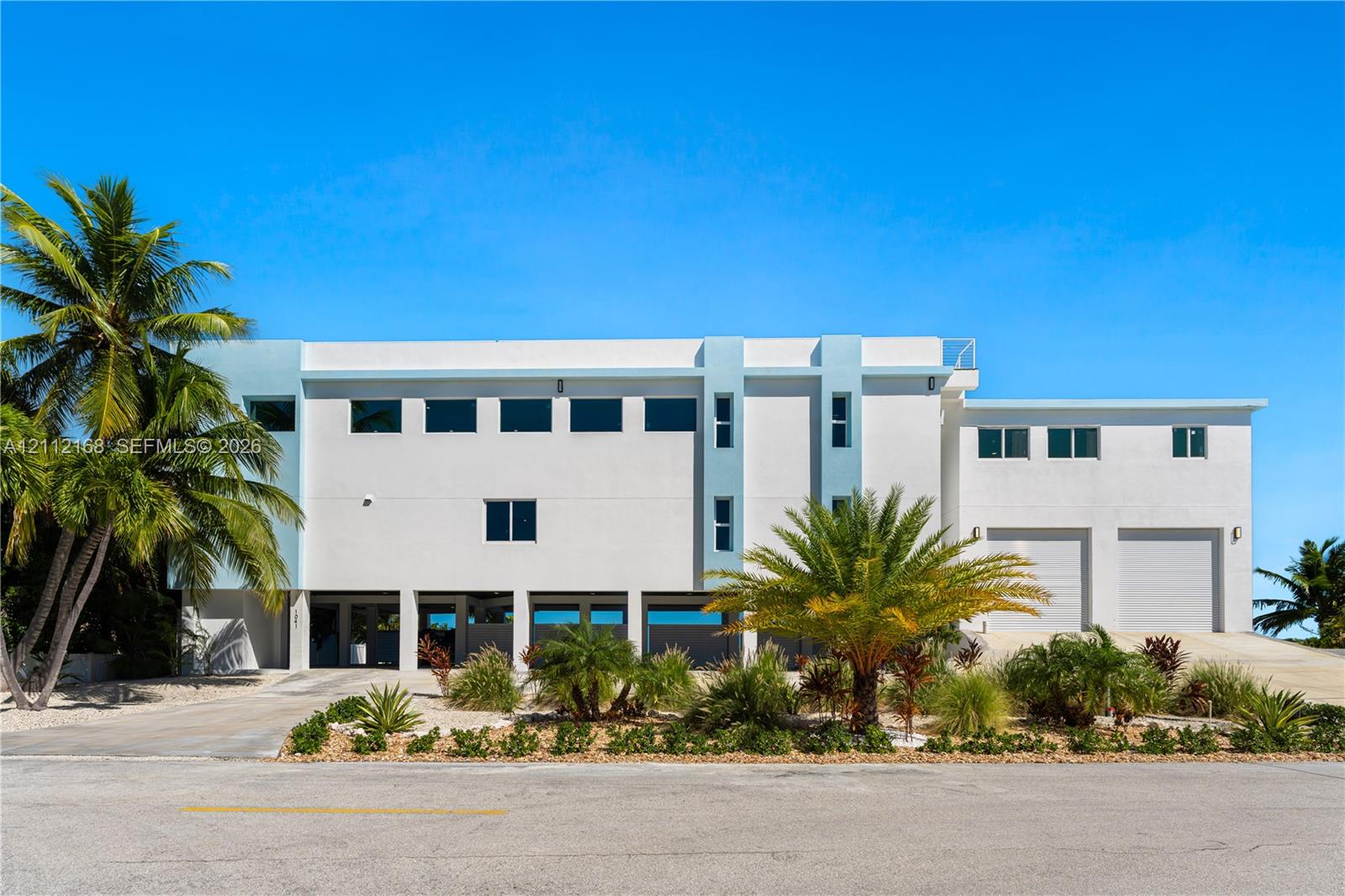 Contemporary multi-level exterior featuring white stucco finish, dual garage bays, expansive windows, and integrated ground-level parking
