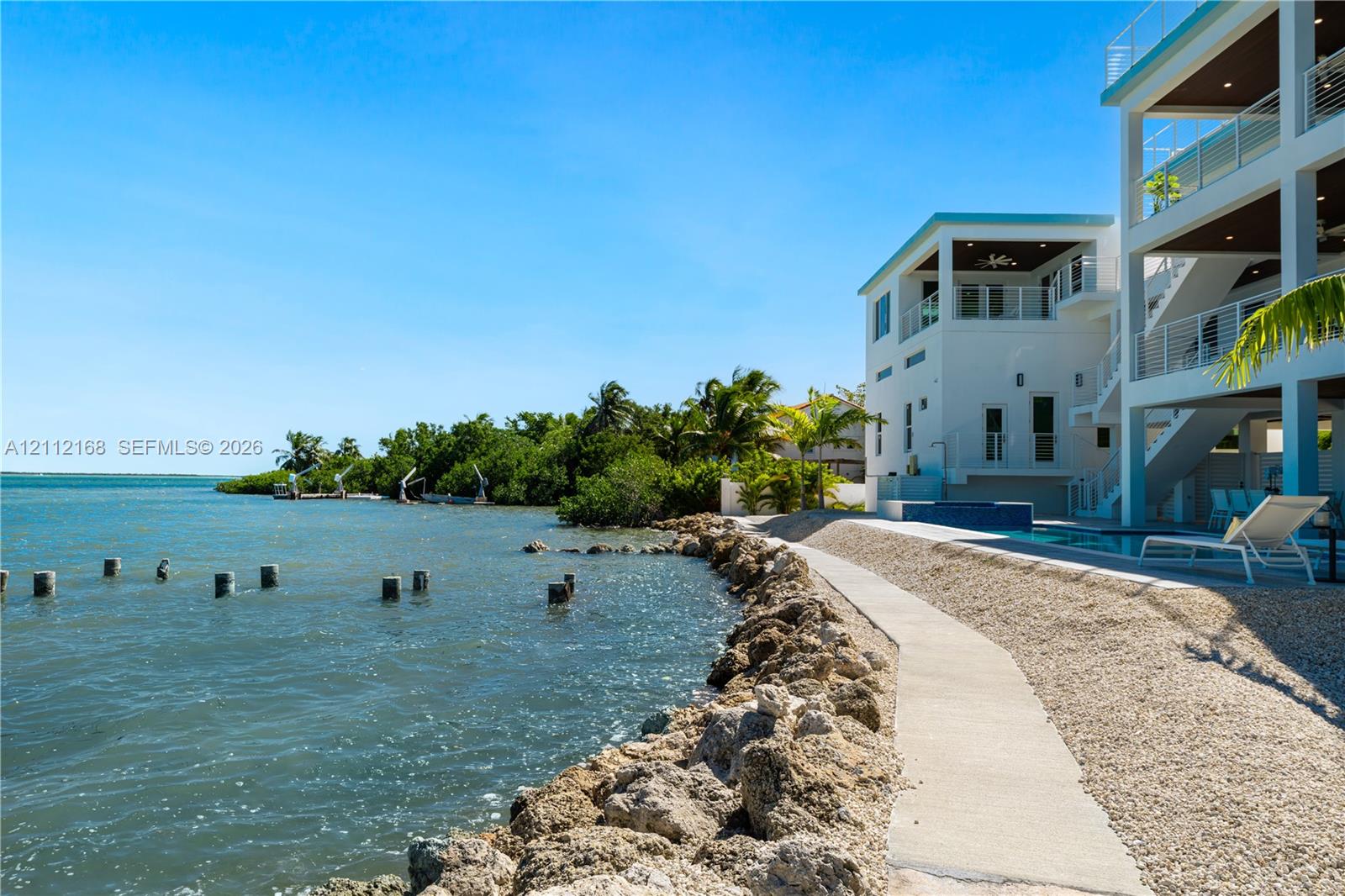 Multi-level coastal residence featuring deep-water access, a private swimming pool, concrete bulkhead, and tiered covered balconies
