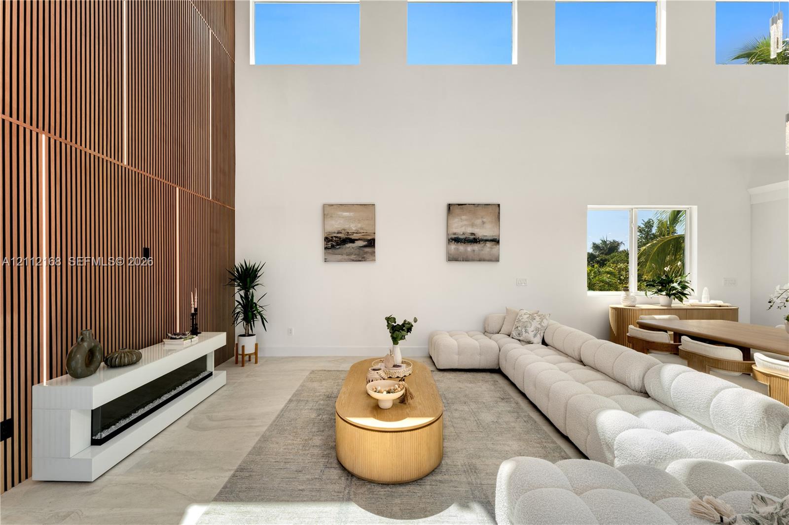 Double-height ceilings with transom windows, full-height vertical wood-slat feature wall, integrated linear fireplace with white floating hearth, and large-format tile flooring
